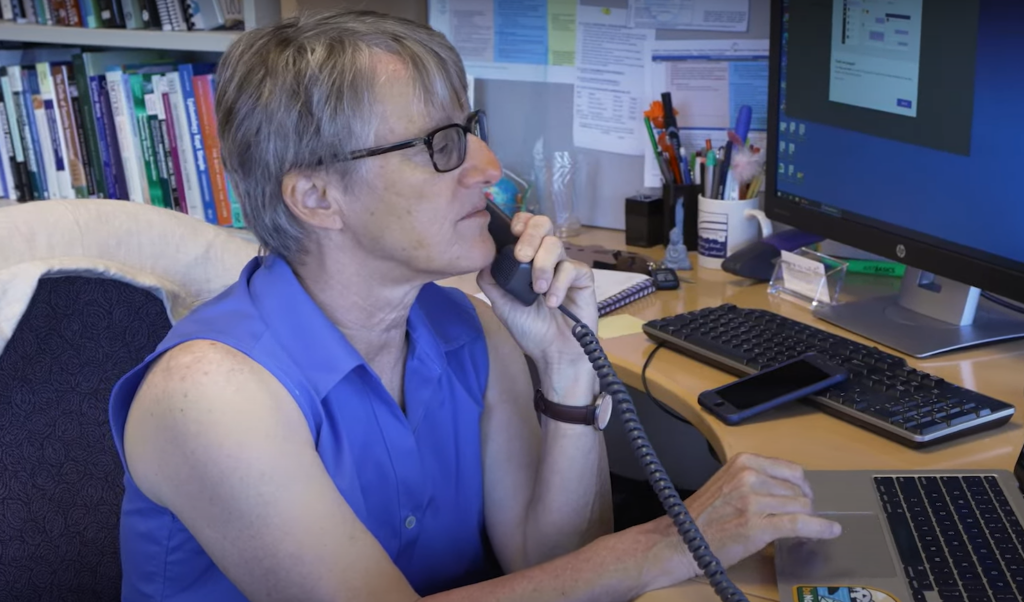 Photo of Dr. Maria Muzik speaking on the telephone and looking at a computer screen