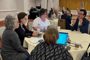 Members of MC3 sit at a round table at the second annual meeting of Pediatric Mental Health Care Access teams