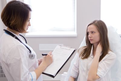 Distressed teen patient listens to her doctor.