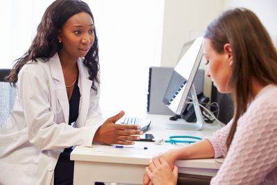 Doctor sits at her desk talking to a distressed teen patient.