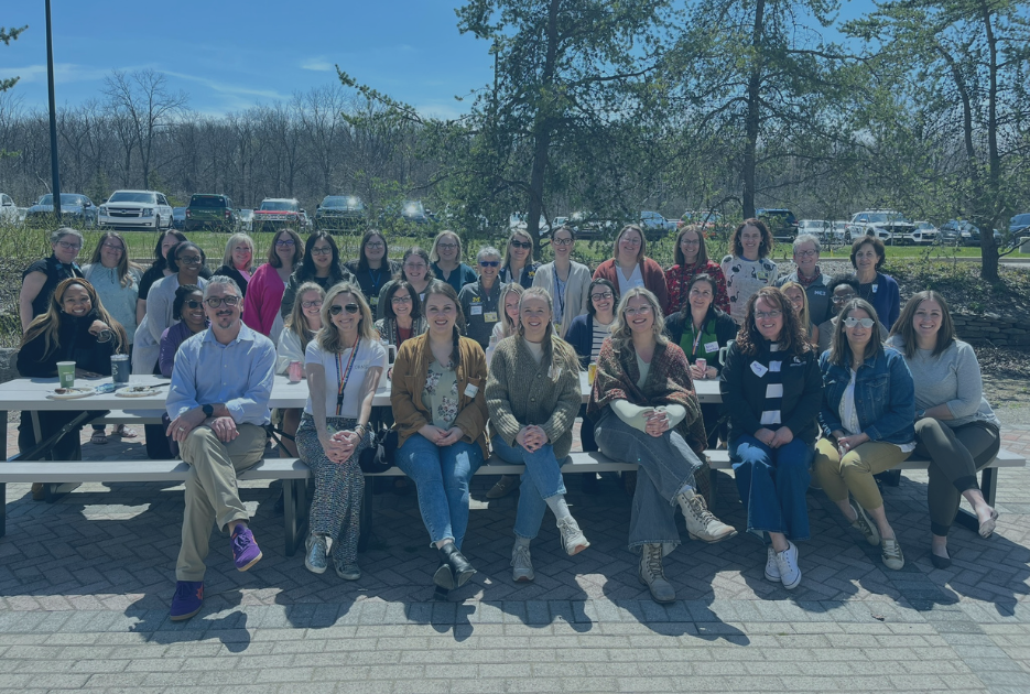 MC3 team members sit at a large picnic table outside.