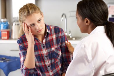 Distressed teen sits across from a doctor.