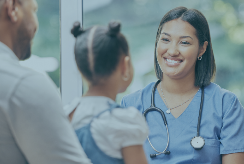 A pediatrician smiles at a patient and her father.