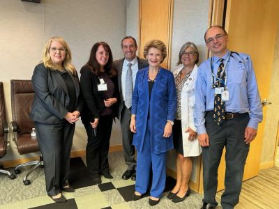 Group photo from HRSA visit in Lansing, Sep. 2023. Subjects from left to right include former HRSA Administrator Carole Johnson, MC3 Behavioral Health Consultant Mindy Evans, former MC3 psychiatrist Richard Dopp, M.D., former Senator Debbie Stabenow, MC3 champion Lia Gaggino, M.D., and pediatrician Yakov Sigal, M.D.