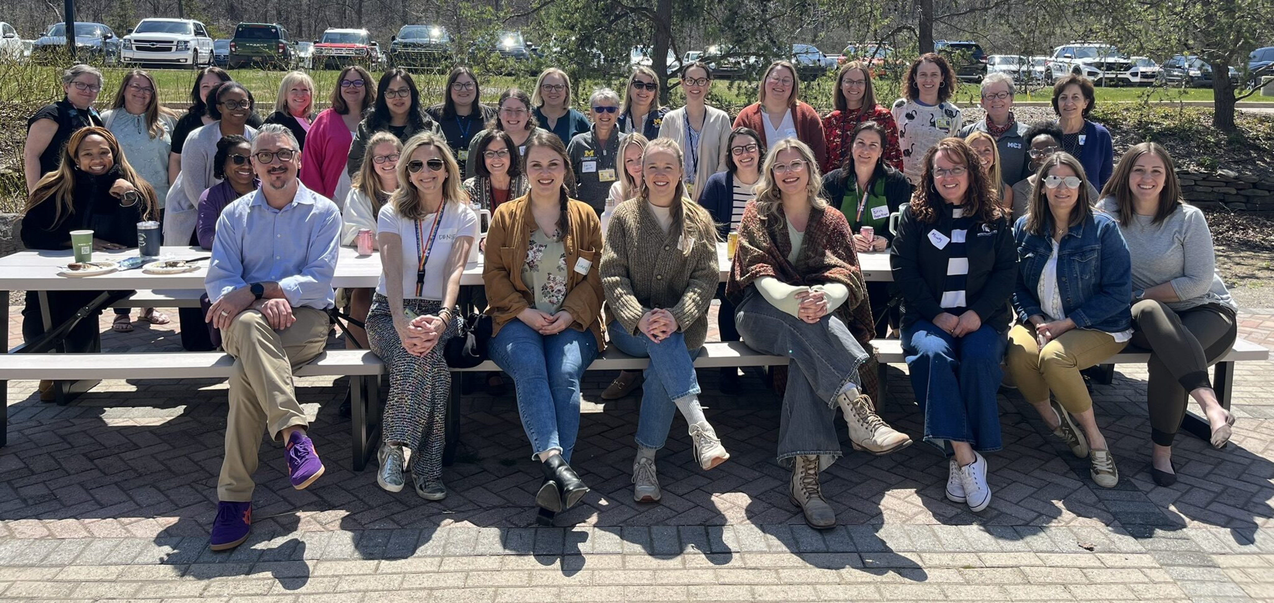 Members of MC3 sit outside at a picnic table during an event.